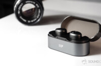 Monoprice cheap true wireless earbuds in case an din front of a black vintage lens.