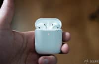 AirPods 2 in wireless charging case held by man's hand.